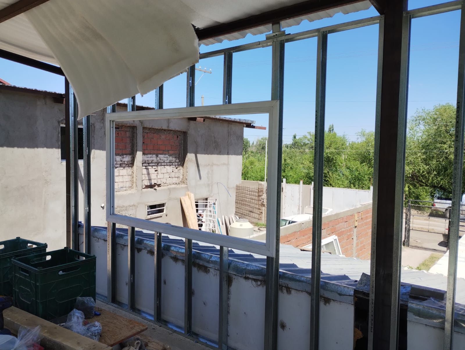Área de construcción en la azotea con estructura metálica, cielo abierto y edificios vecinos al fondo.