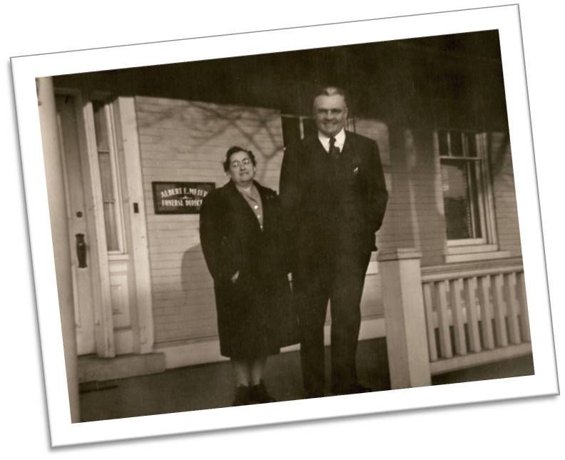 A black and white photo of a man and woman standing on a porch