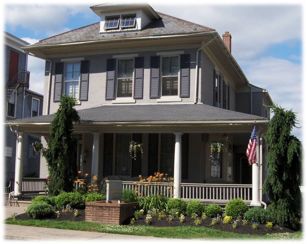 A large house with a large porch and an american flag