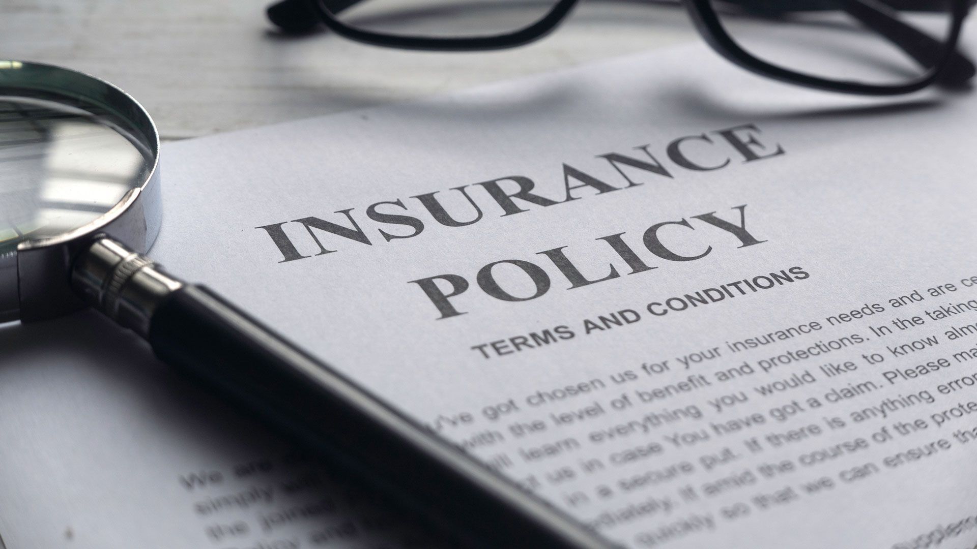 a magnifying glass is sitting on top of an insurance policy .