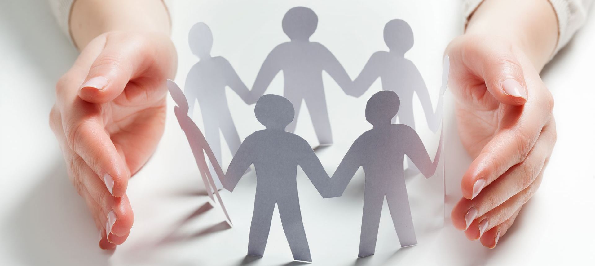 a person is holding a group of paper people holding hands