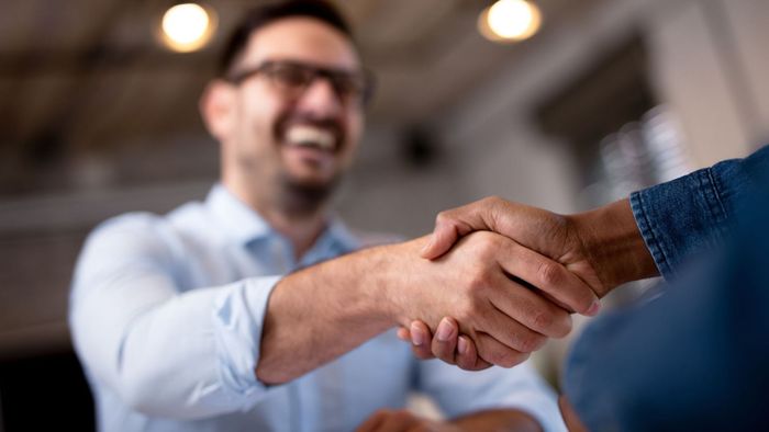 a man is shaking hands with another man while sitting at a table