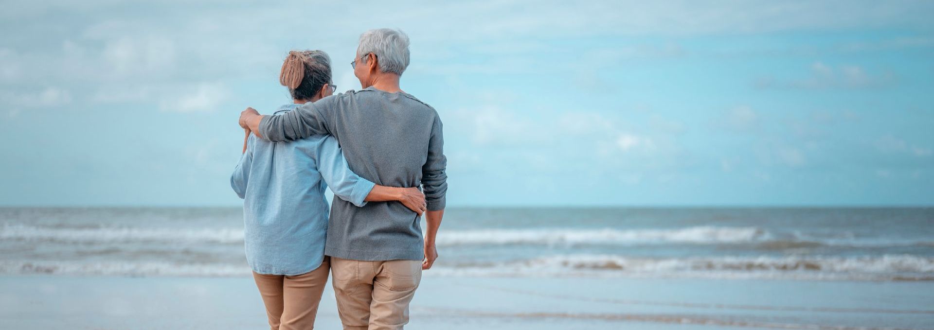 a man and a woman are standing on a beach looking at the ocean