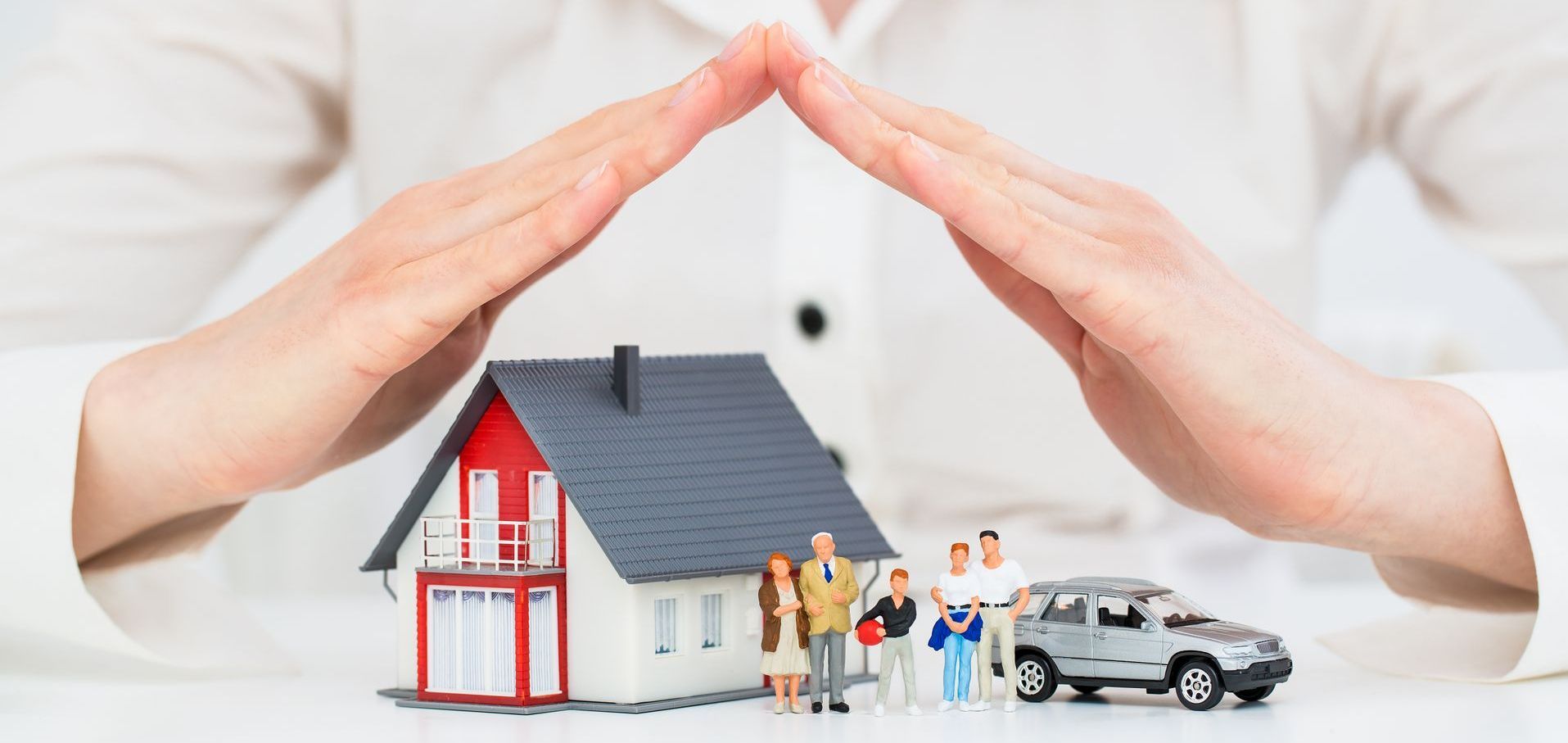 a woman is covering a house and a car with her hands .
