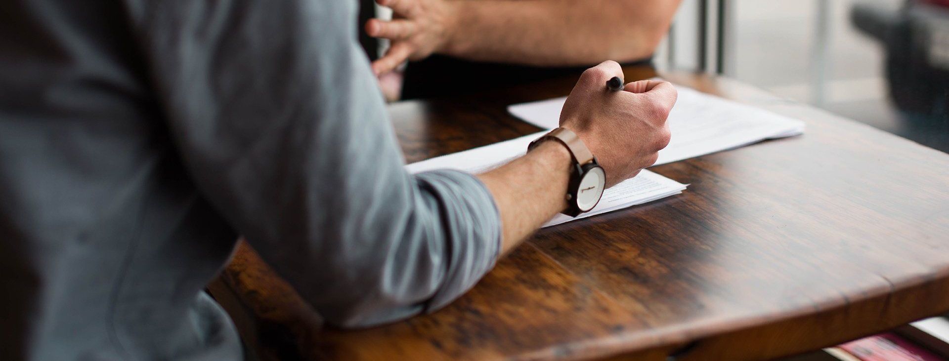a man is sitting at a table with a pen in his hand .