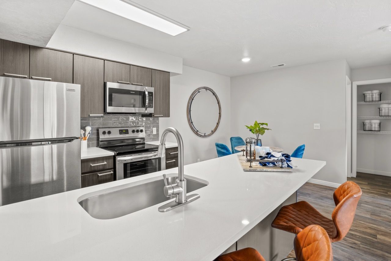 Modern kitchen with stainless steel appliances, a large white island, and seating. Plan your visit to Turnberry Apartments and explore renovated apartments for rent in Millcreek, UT, designed for modern lifestyles.