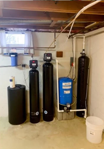 A basement with three water filters and a water pump.