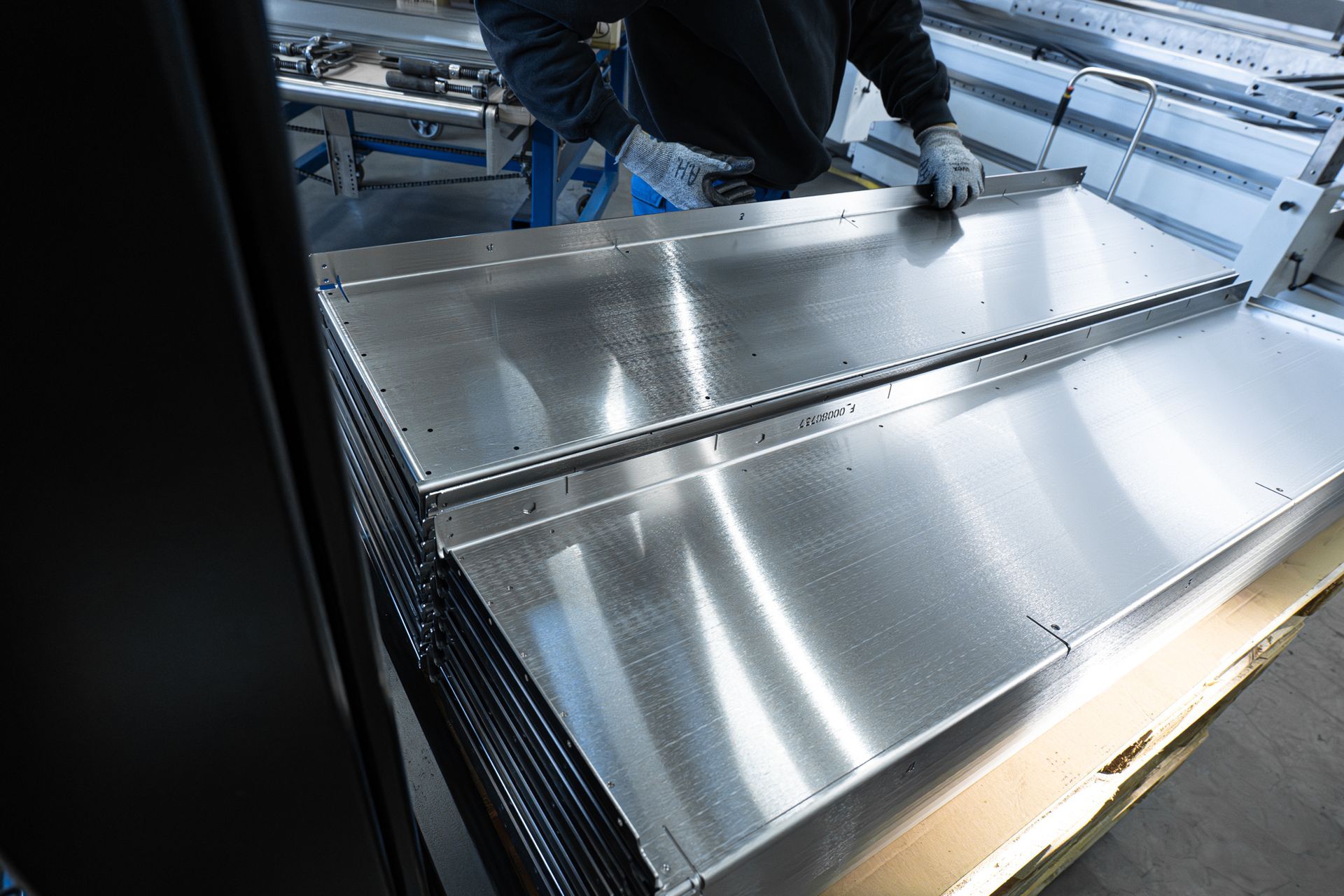 Arbeiter montieren glänzende Metallpaneele in einer industriellen Fabriklinie