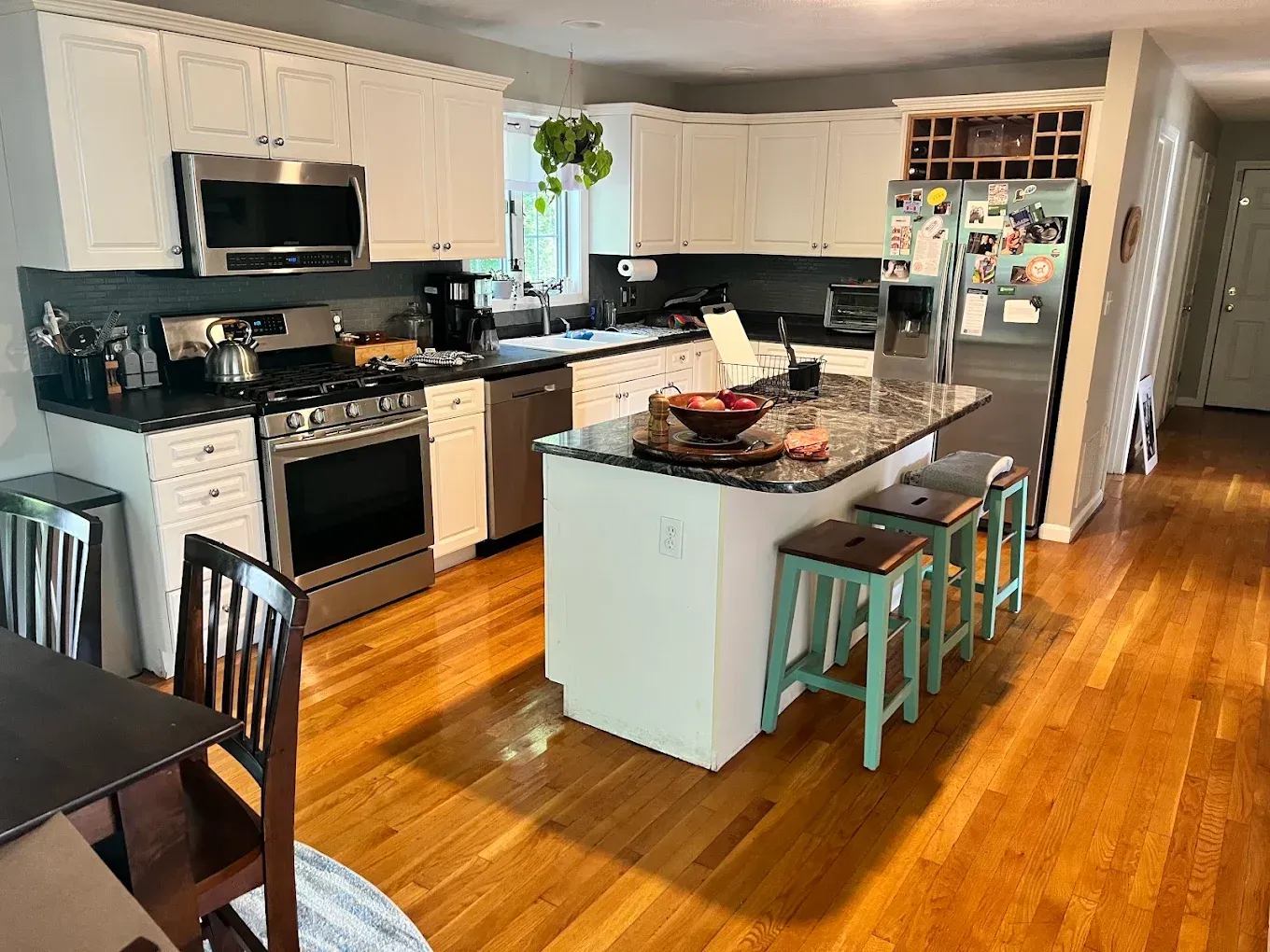 Bright kitchen with white cabinets, black countertops, island, and hardwood floors