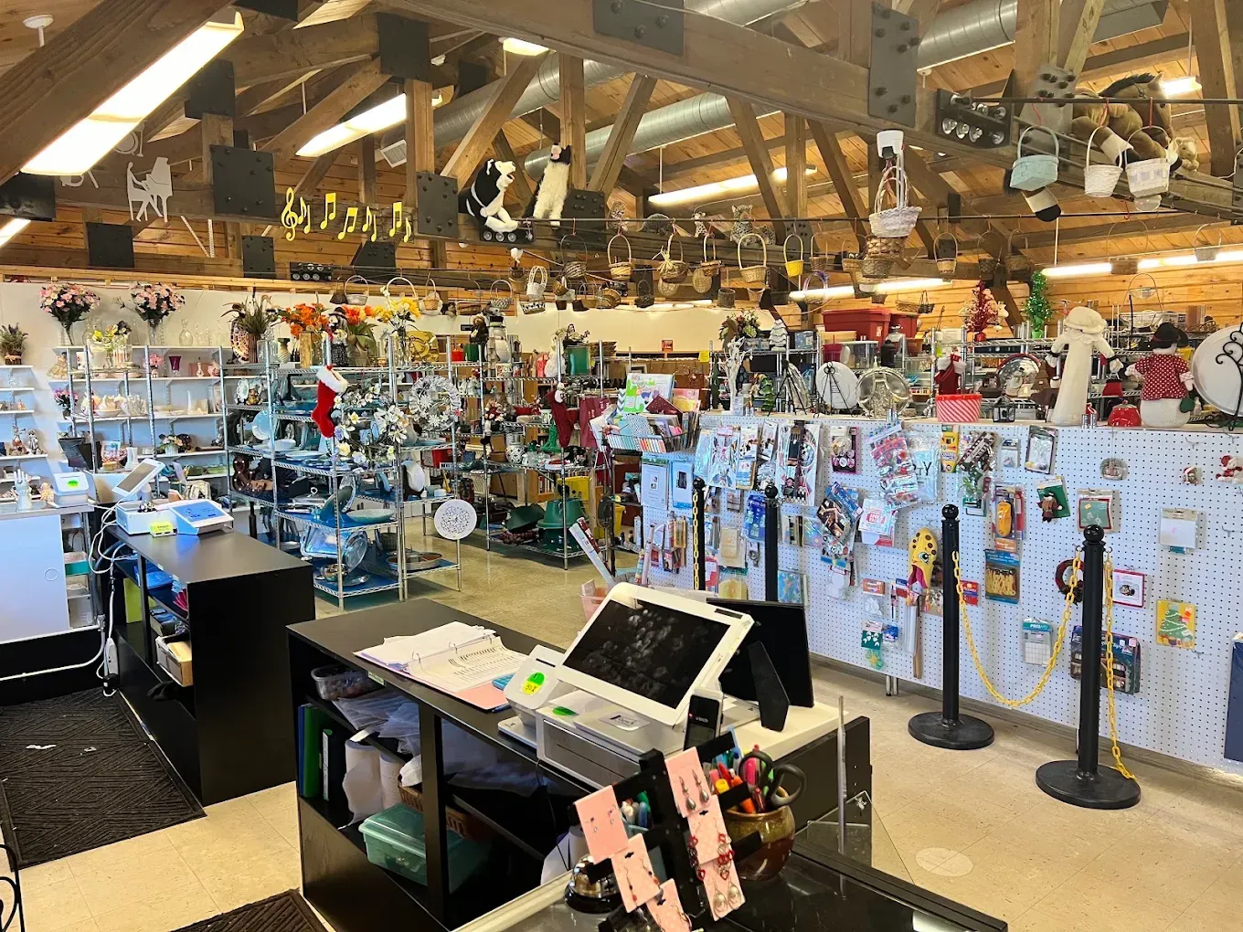 Gift shop interior with shelves of souvenirs, hanging items, and a checkout counter under warm lighting