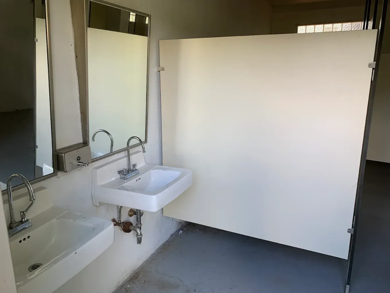 Bathroom with white sink, bathtub, large mirror, and a partial white partition wall