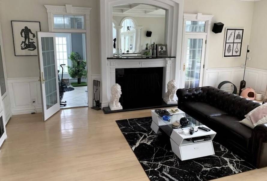 Bright living room with black sofa, marble coffee table, fireplace, and light wood floors