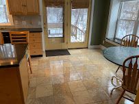 Small kitchen with tiled floor, wooden cabinets, dining table, and windows looking out onto snow.