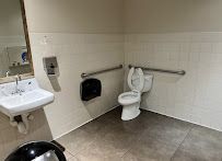 Accessible restroom with a toilet, sink, grab bar, and wall-mounted paper dispenser.