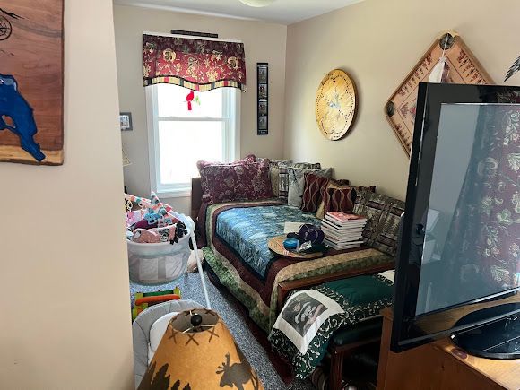 Cozy bedroom with a daybed, patterned bedding, window, wall art, and a TV in the foreground