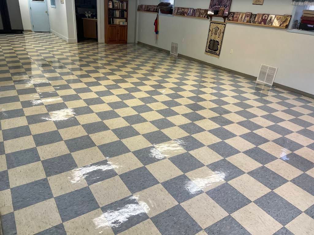 Empty tiled hallway with black-and-white checkerboard floor and a wall-mounted counter on the right.