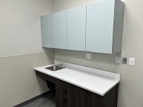 Office kitchenette with white sink counter, pale blue cabinets, and gray walls