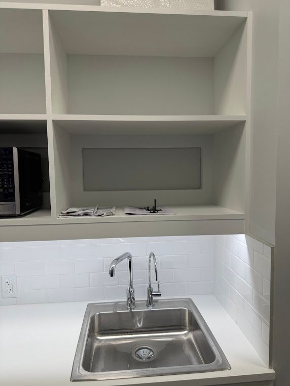 Kitchen sink beneath white shelves with built-in under-cabinet lighting