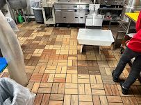 Commercial kitchen with a patterned tile floor, stainless steel counters, and a person standing at right.