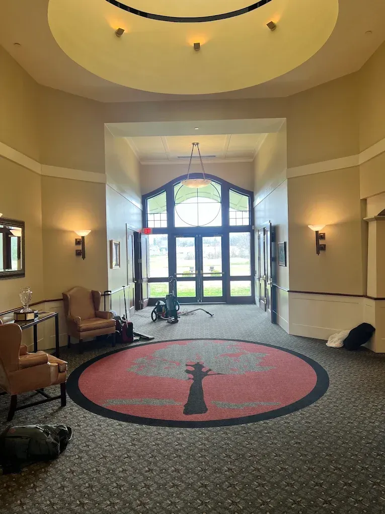 Hotel lobby with patterned carpet, red circular rug, chairs, and bright glass entrance doors