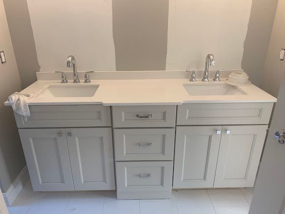 White double bathroom vanity with two sinks and gray cabinets against a beige wall