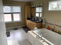 Bright kitchen with white tile floor, wooden cabinets, sink, mirror, and large windows