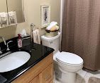 Small bathroom with black vanity, white toilet, and beige shower curtain.