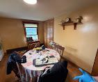 Dining room with a round table, chairs, window, and wall shelves in a beige room.