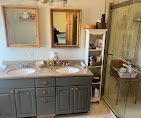 Bathroom vanity with double sinks, mirror cabinet, and glass shower doors in a beige room