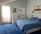 Blue bedroom with a bed, dresser, and window with curtains