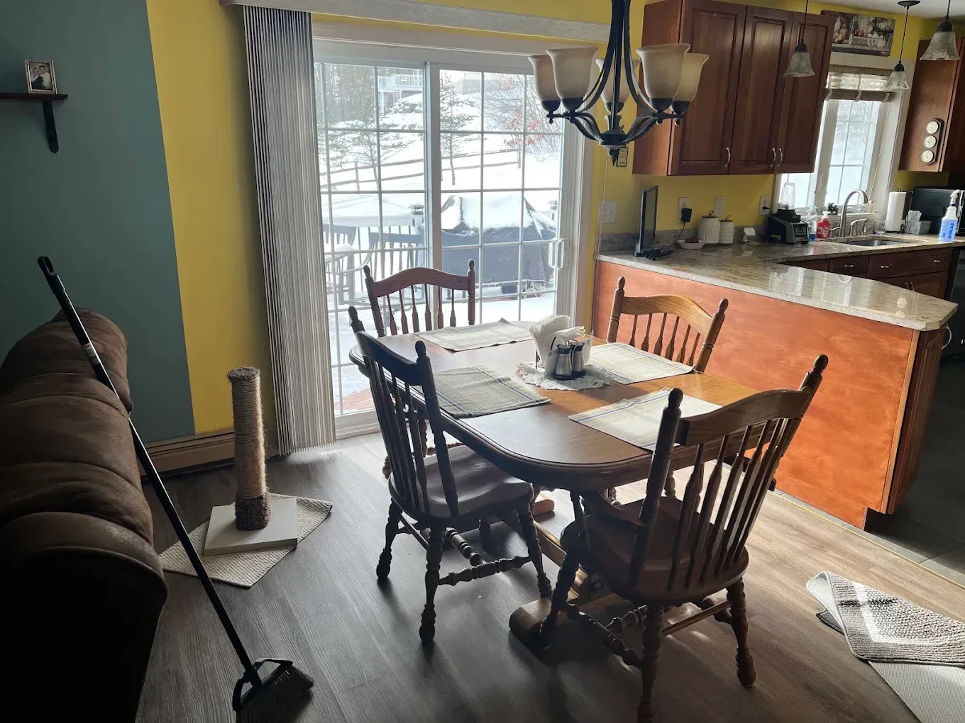 Dining area with wooden table and chairs beside a sliding glass door in a kitchen-living room space
