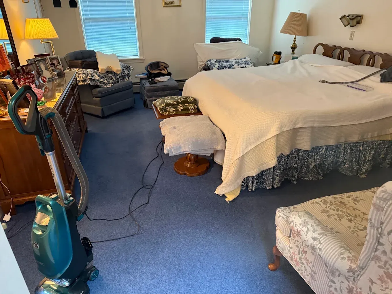 Bedroom with blue carpet, a bed, chair, and exercise equipment near the window