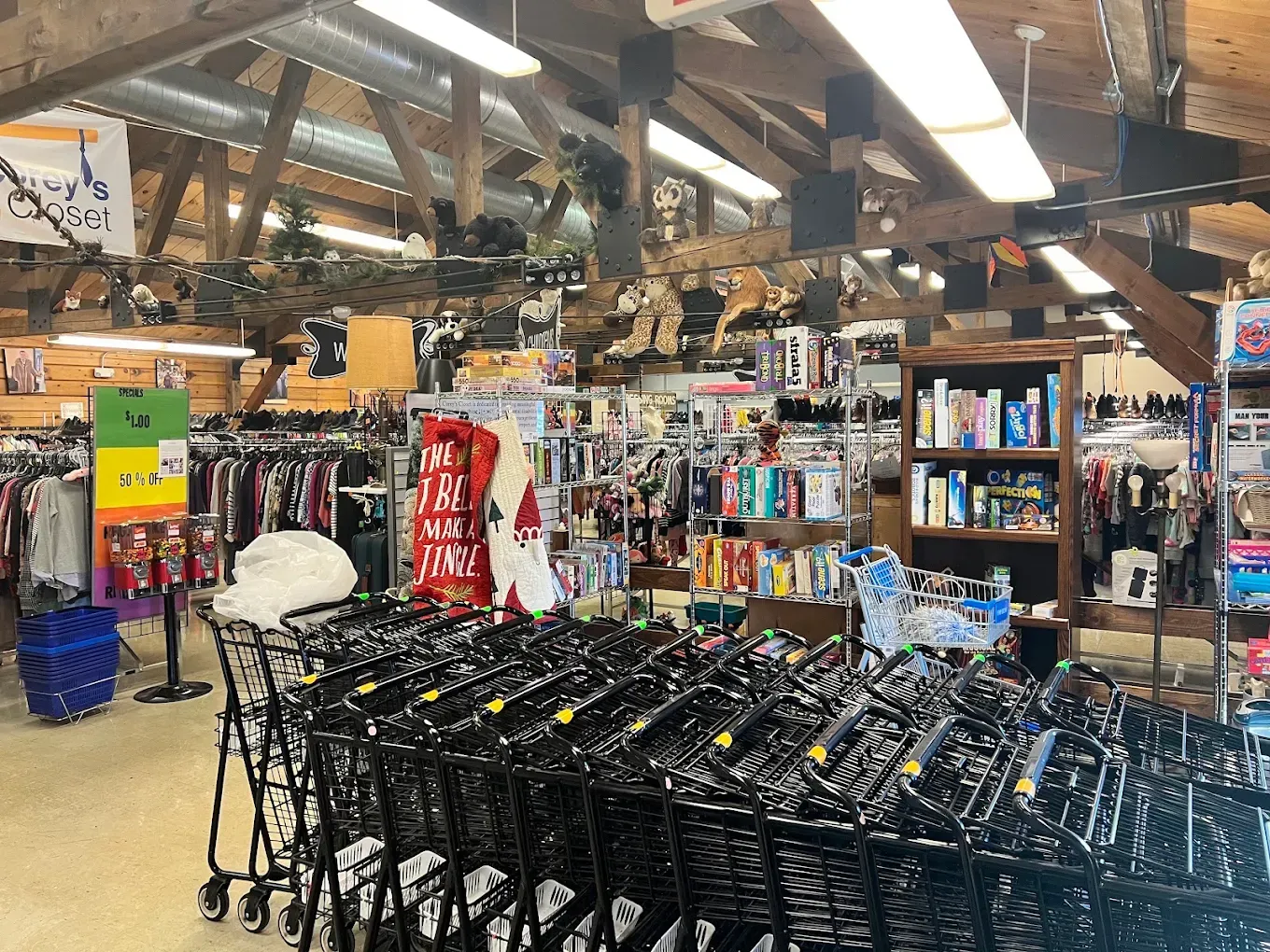 Grocery store aisle with stacked black shopping carts, shelves of products, and bright overhead lights
