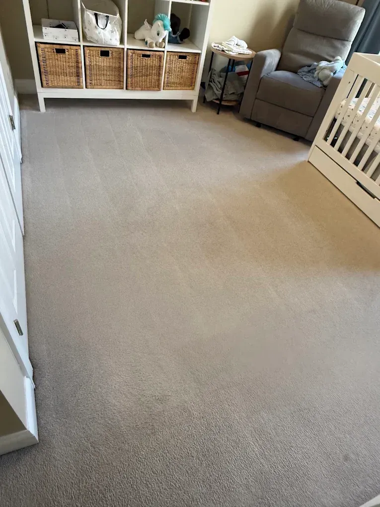 Carpeted nursery with crib, rocking chair, and storage cubbies along the wall