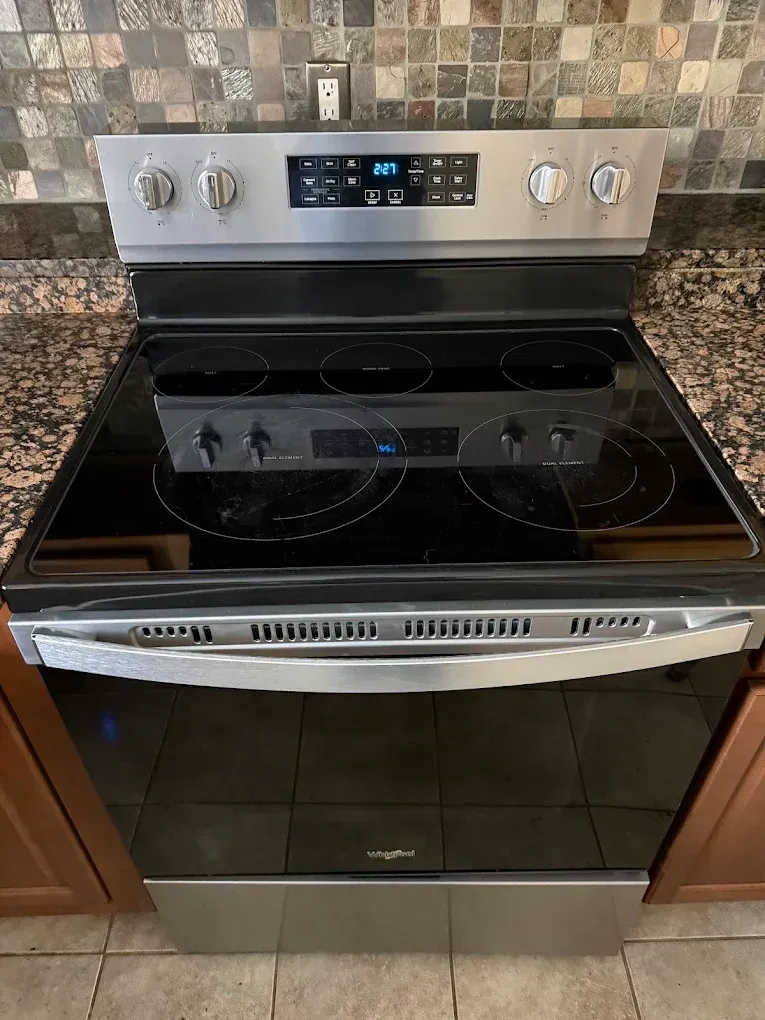 Black stainless steel electric oven and stovetop with digital controls in a kitchen.