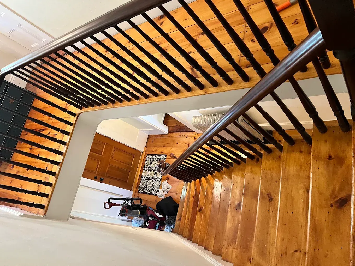 Top-down view of a wooden staircase with black railings and a bicycle at the bottom landing