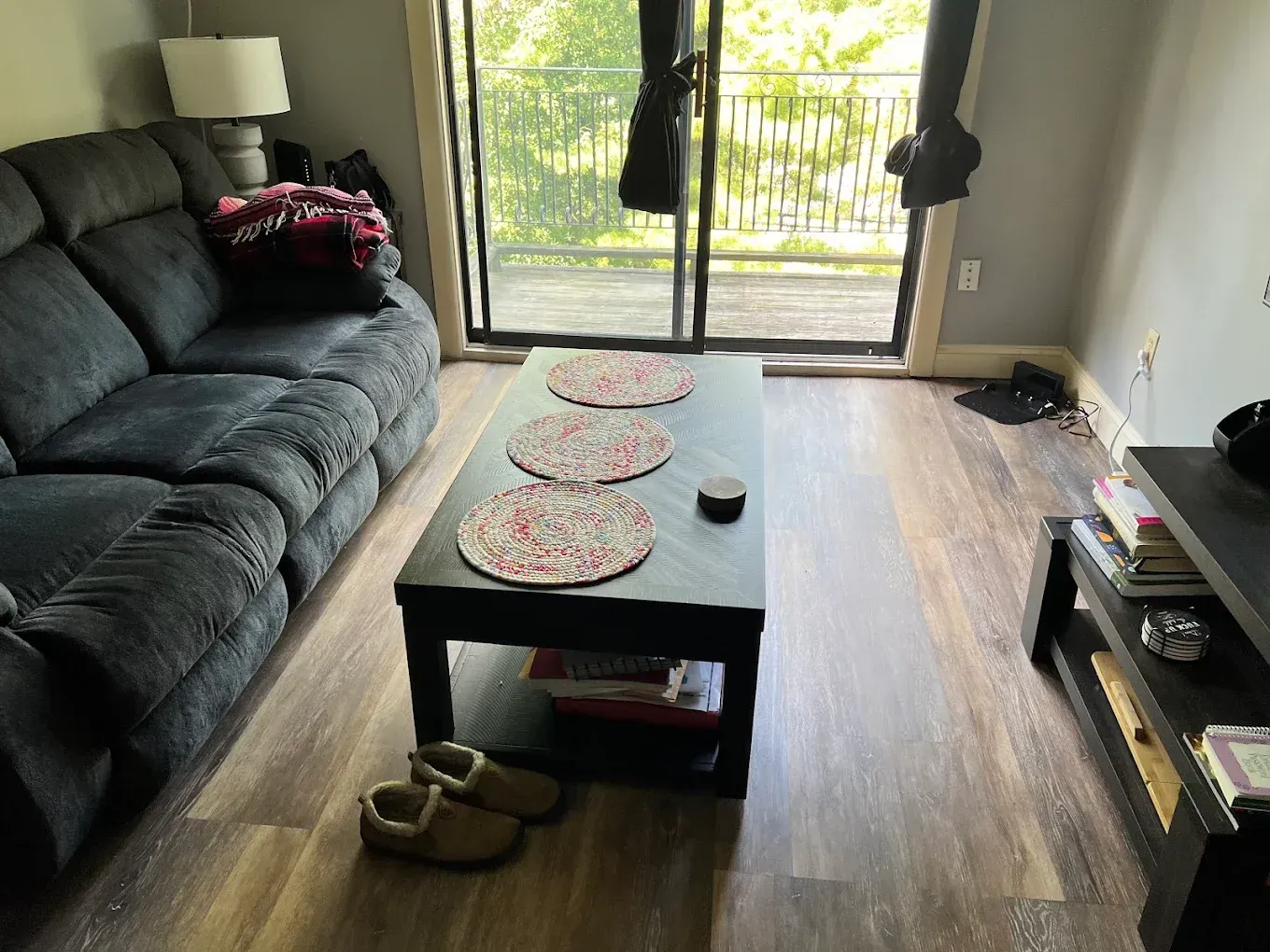 Living room with gray sofa, coffee table, rug, and sliding glass door to a balcony.