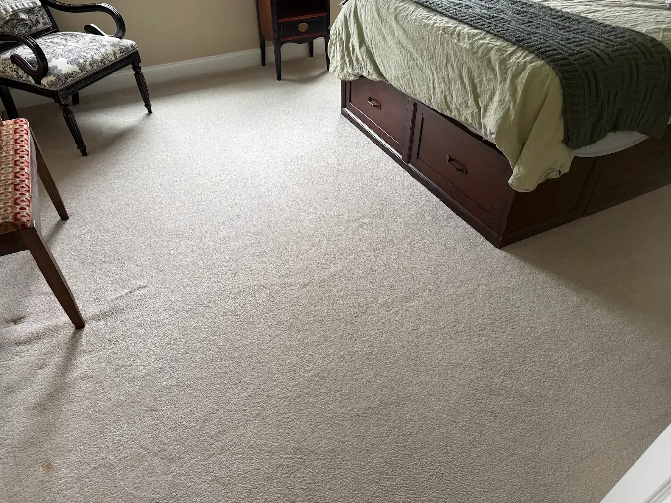 Carpeted bedroom with a bed, chairs, and a small table by the wall