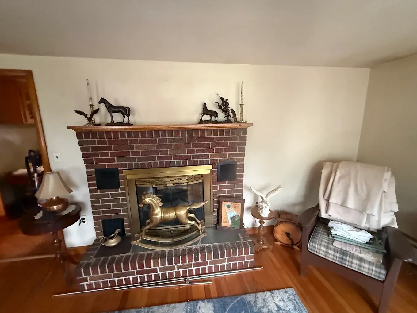Brick fireplace with brass screen in a cozy living room, decorated with animal figurines and a recliner nearby