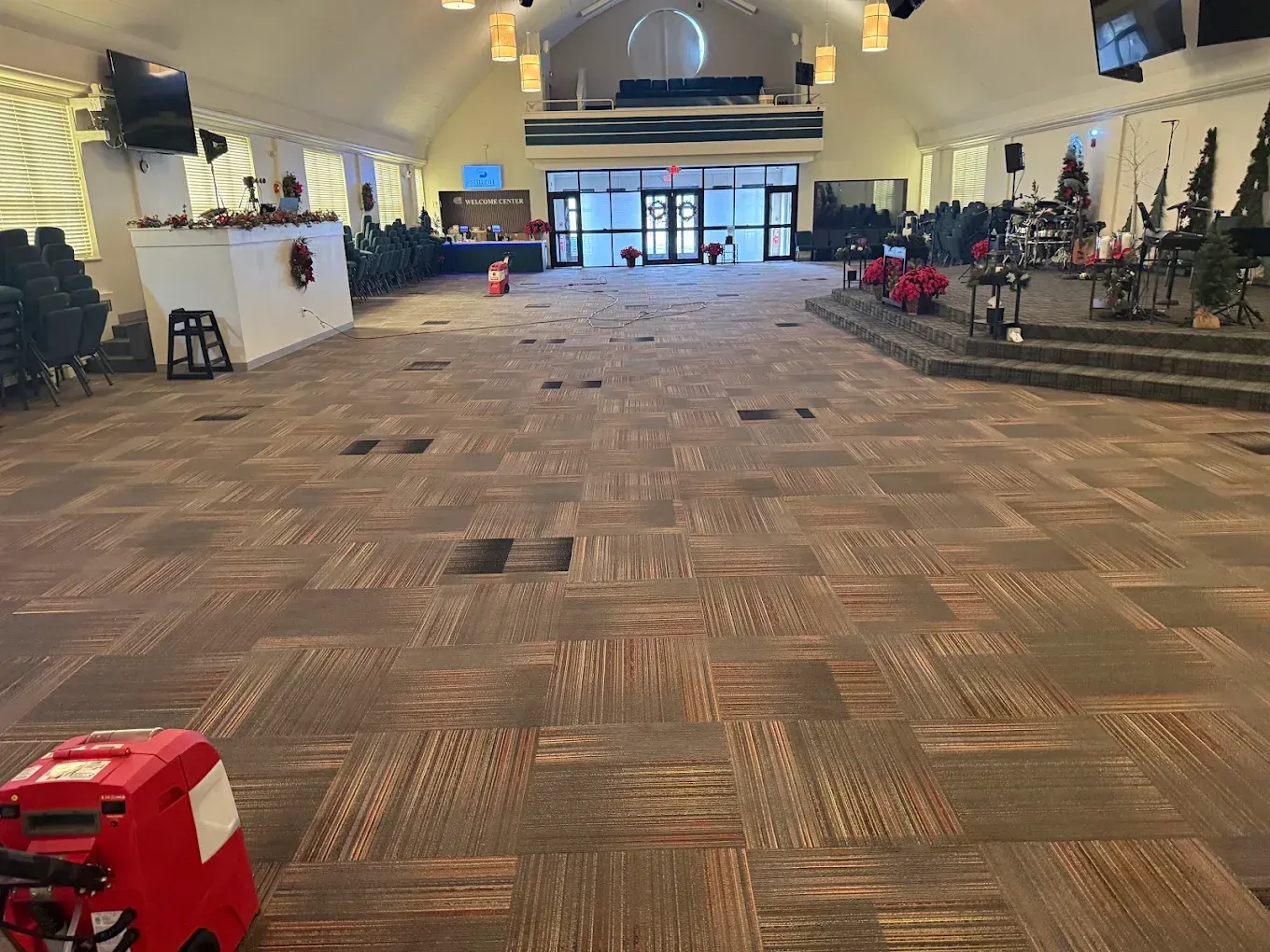 Large empty church hall with patterned carpet, stage, pews, and decorations at the front