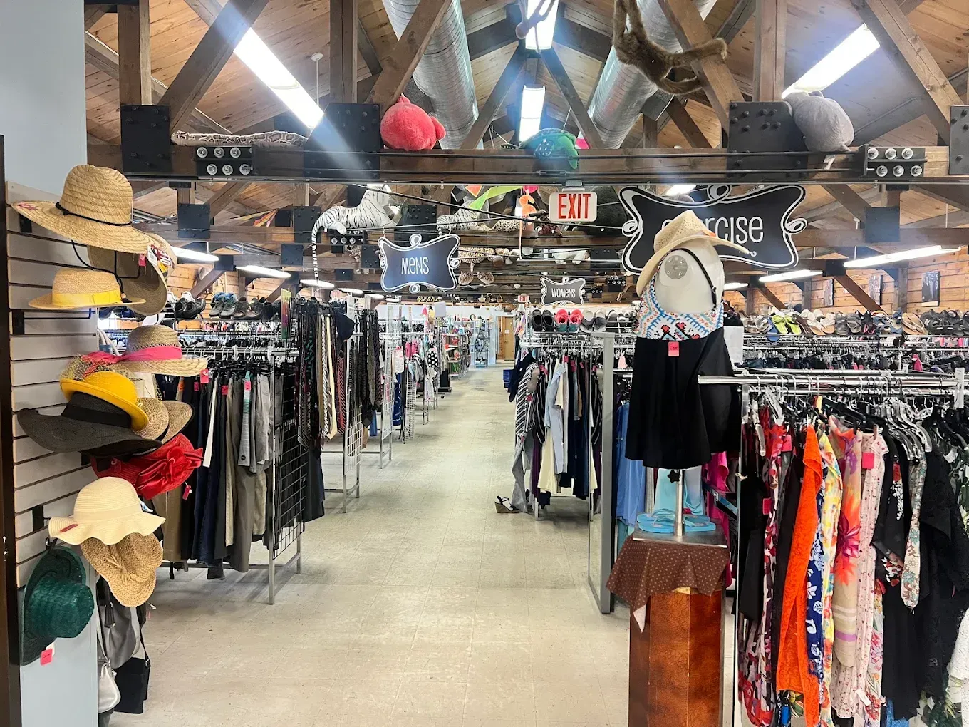 Clothing store interior with racks of clothes and hats under exposed wooden beams