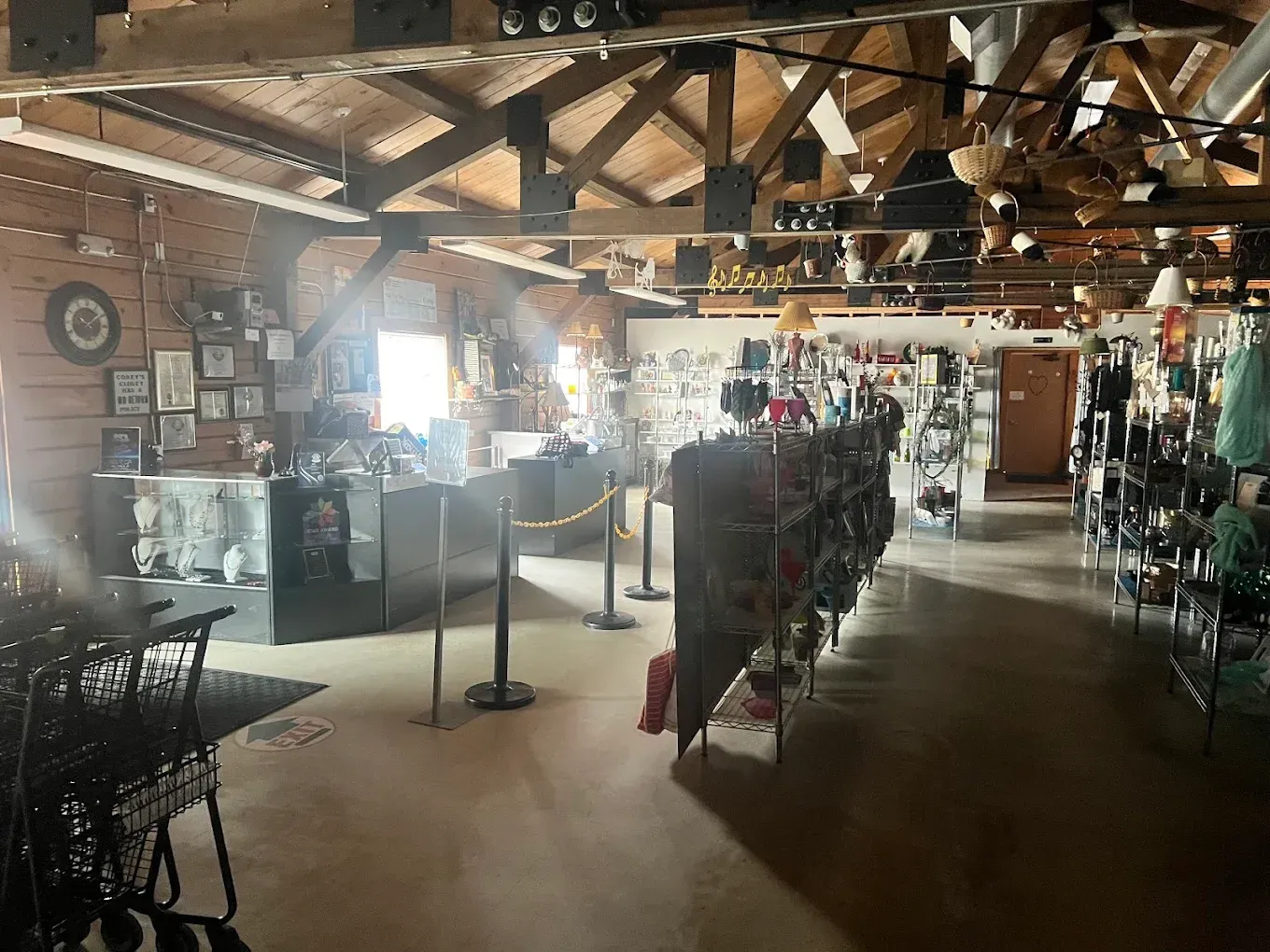 Rustic indoor shop with wooden beams, display racks, and assorted merchandise under warm light