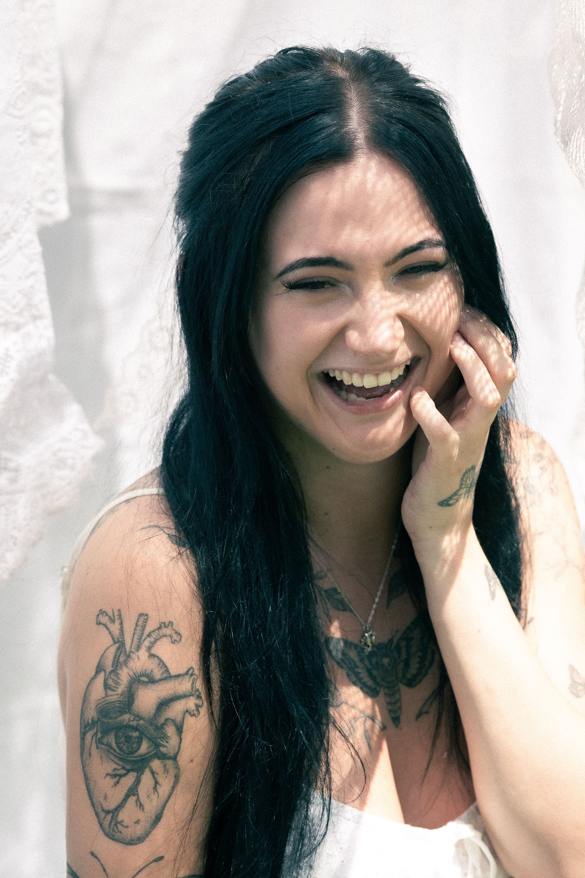 A woman with a tattoo of a heart on her arm is smiling.