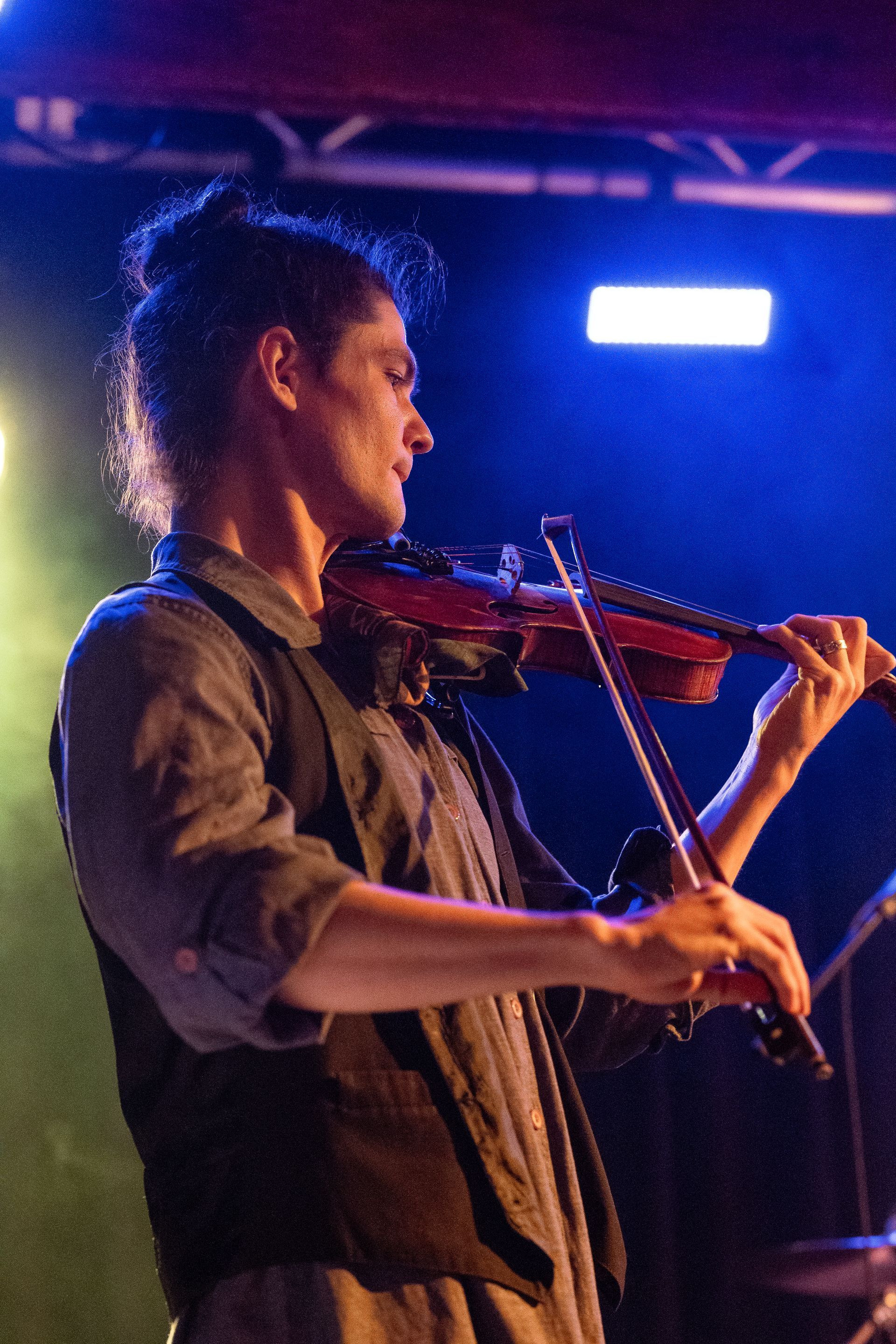 A man is playing a violin in a dark room
