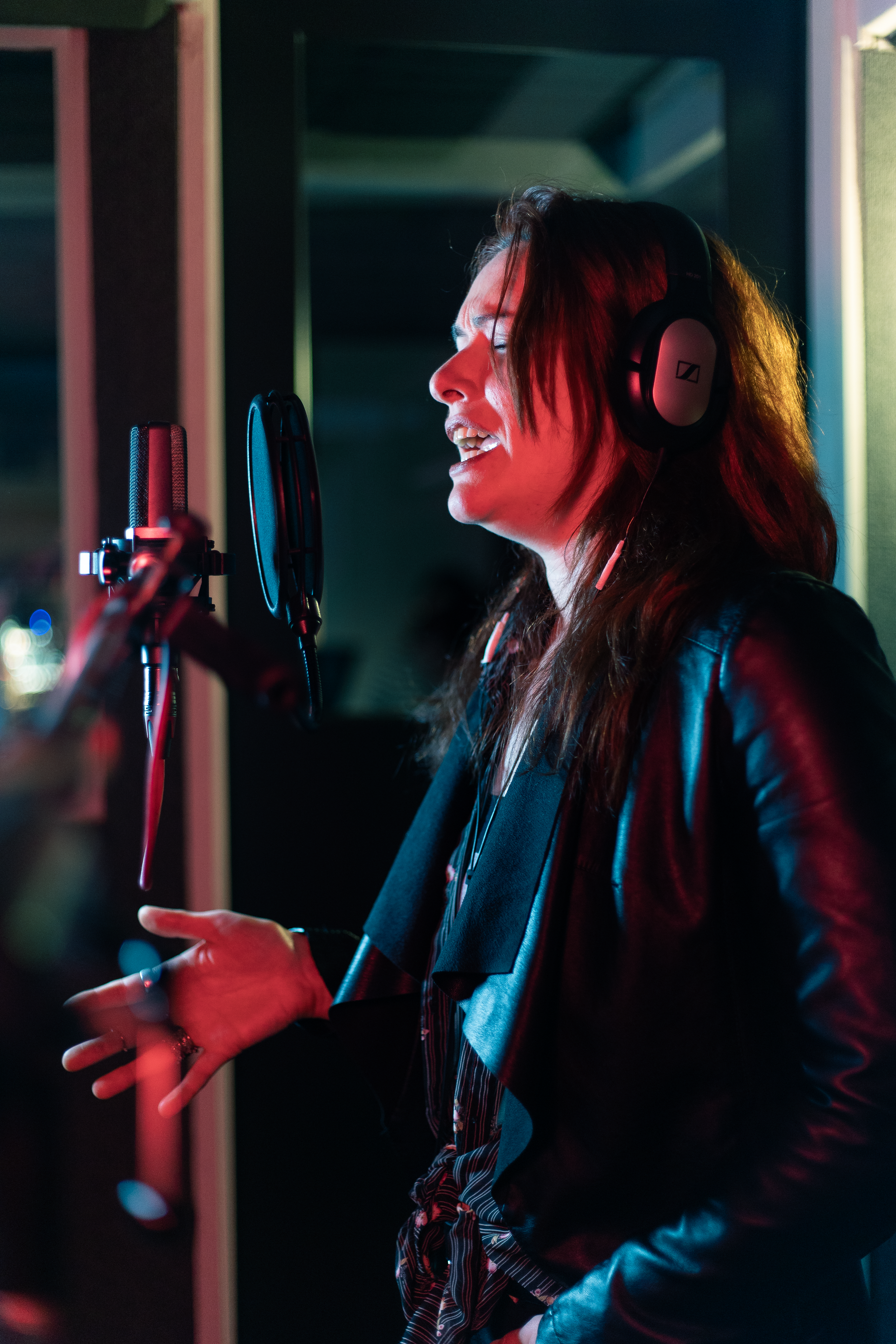 A woman is singing into a microphone in a recording studio.