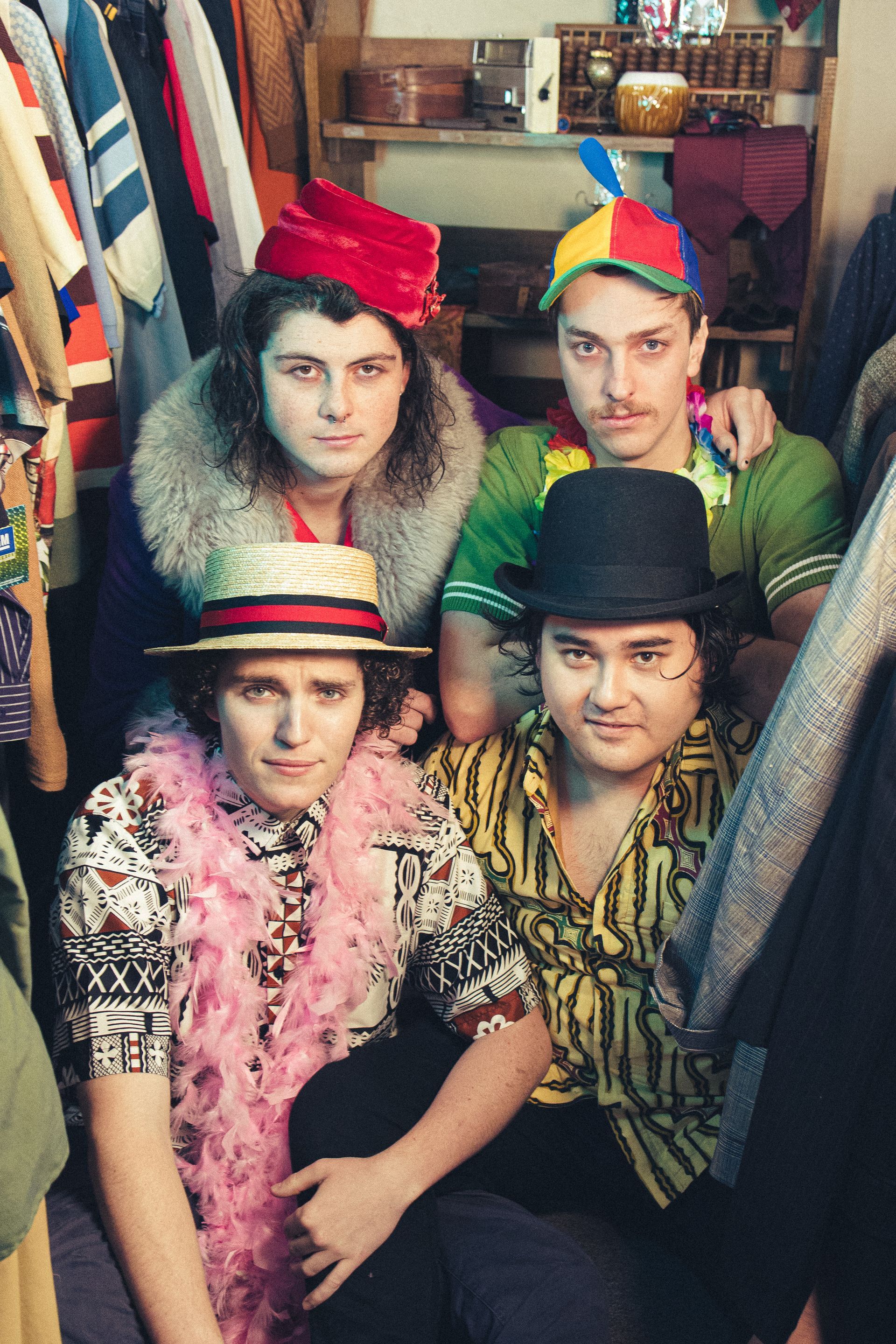 A group of men are posing for a picture in a closet.
