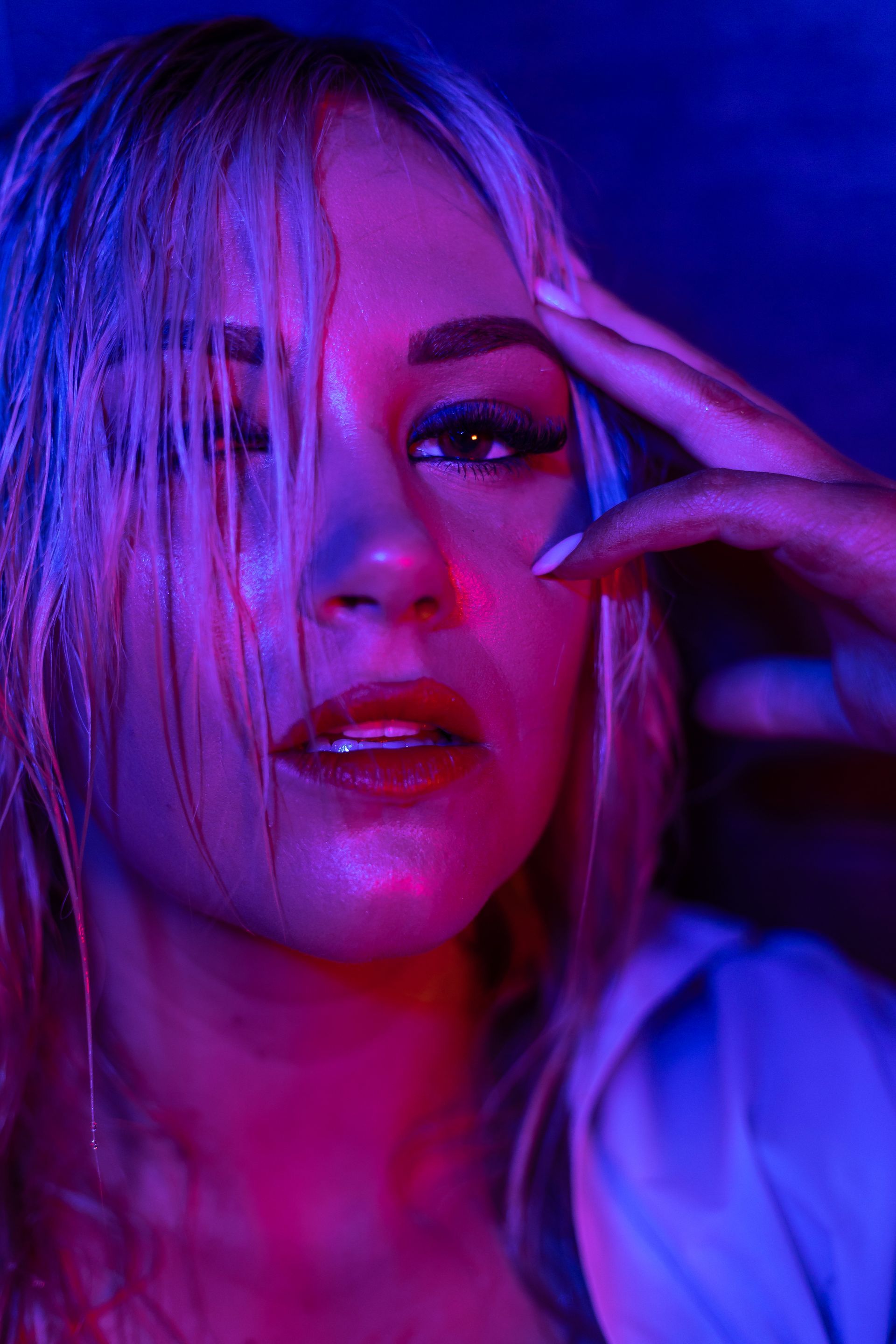 A close up of a woman 's face with red and blue lights behind her.
