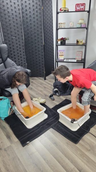 Two children with feet in foot baths at a salon.