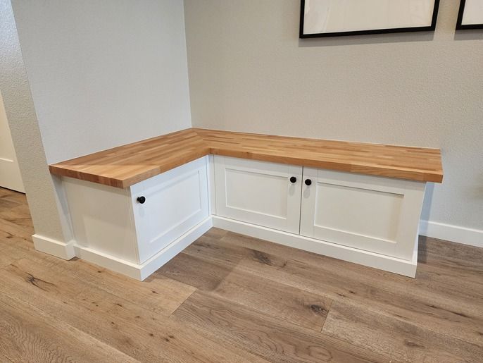 A bench with a wooden top and white cabinets in a hallway.