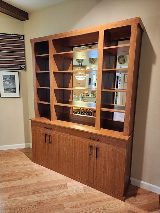 A large wooden cabinet with shelves and doors in a living room.